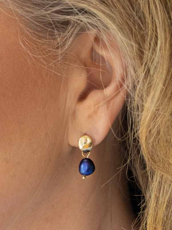 Ett mörkblått pärlörhänge med en välvd guldtopp.