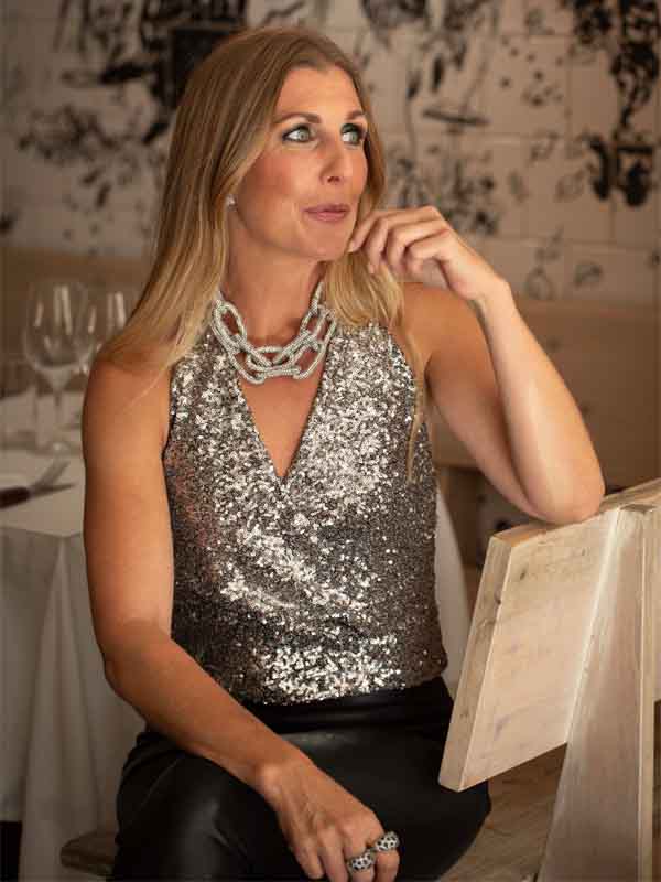 En kvinna i glittertopp och ett stort halsband som glittrar.